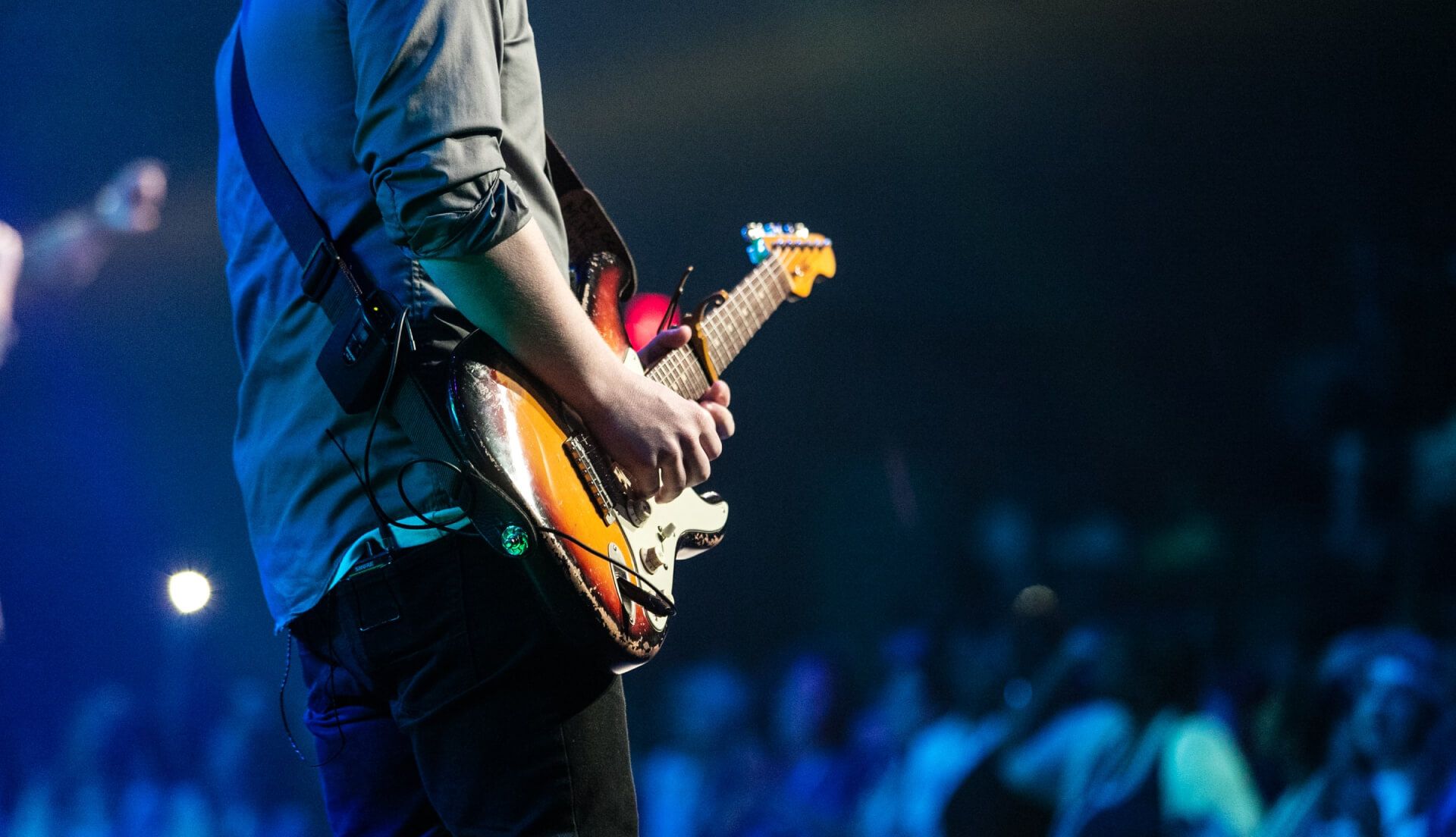 musician playing electric guitar on stage at an event
