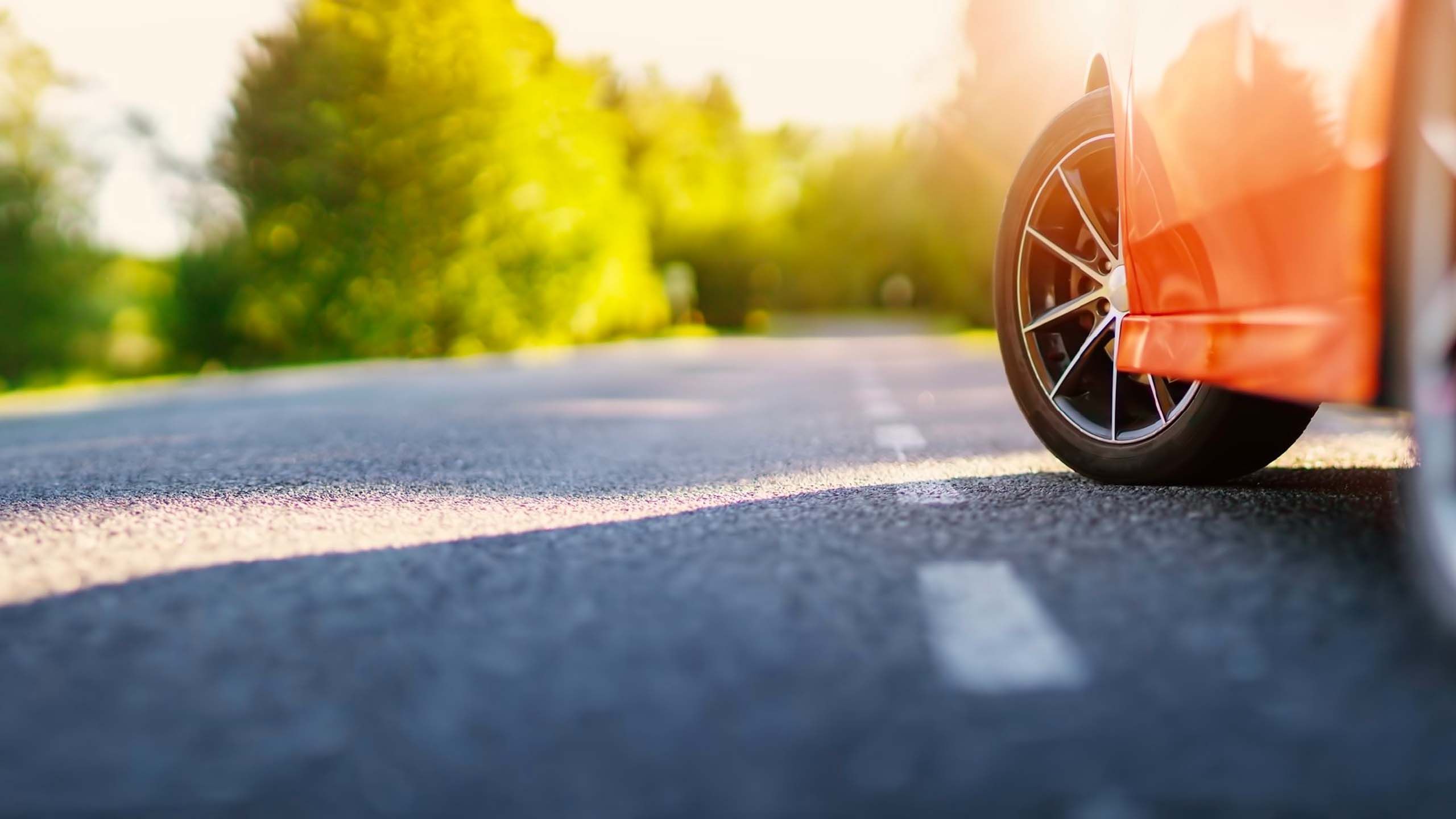 close-up of a car tire on a road with trees in background