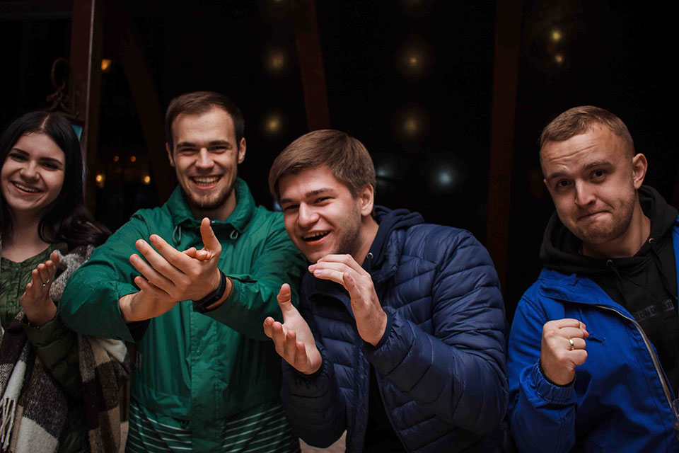 four people celebrating with smiles and clapping hands