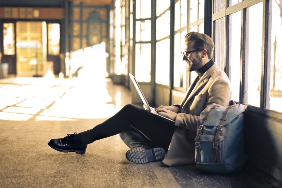 man using laptop while sitting on floor in a bright space