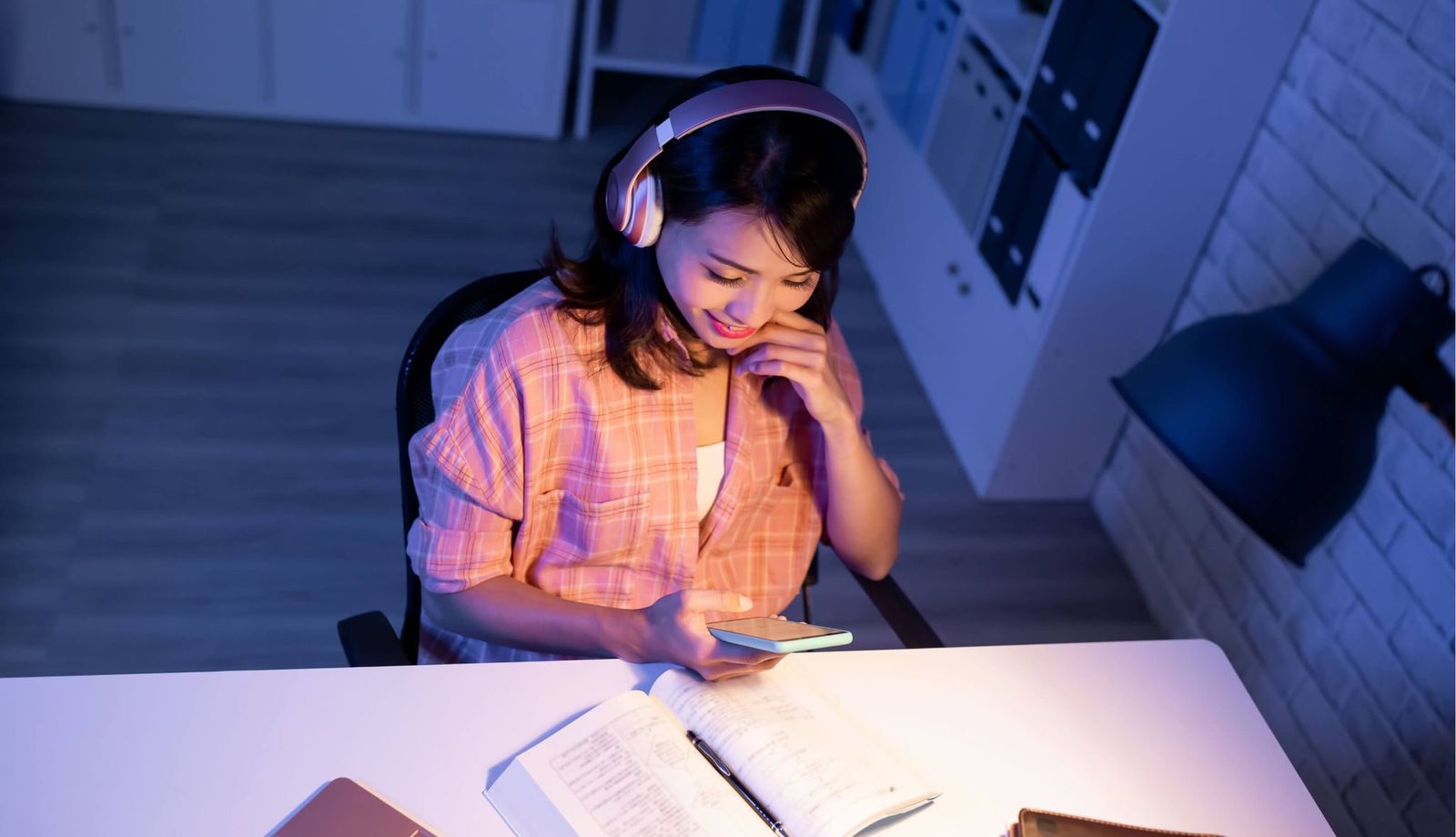student studying with headphones and smartphone at a desk