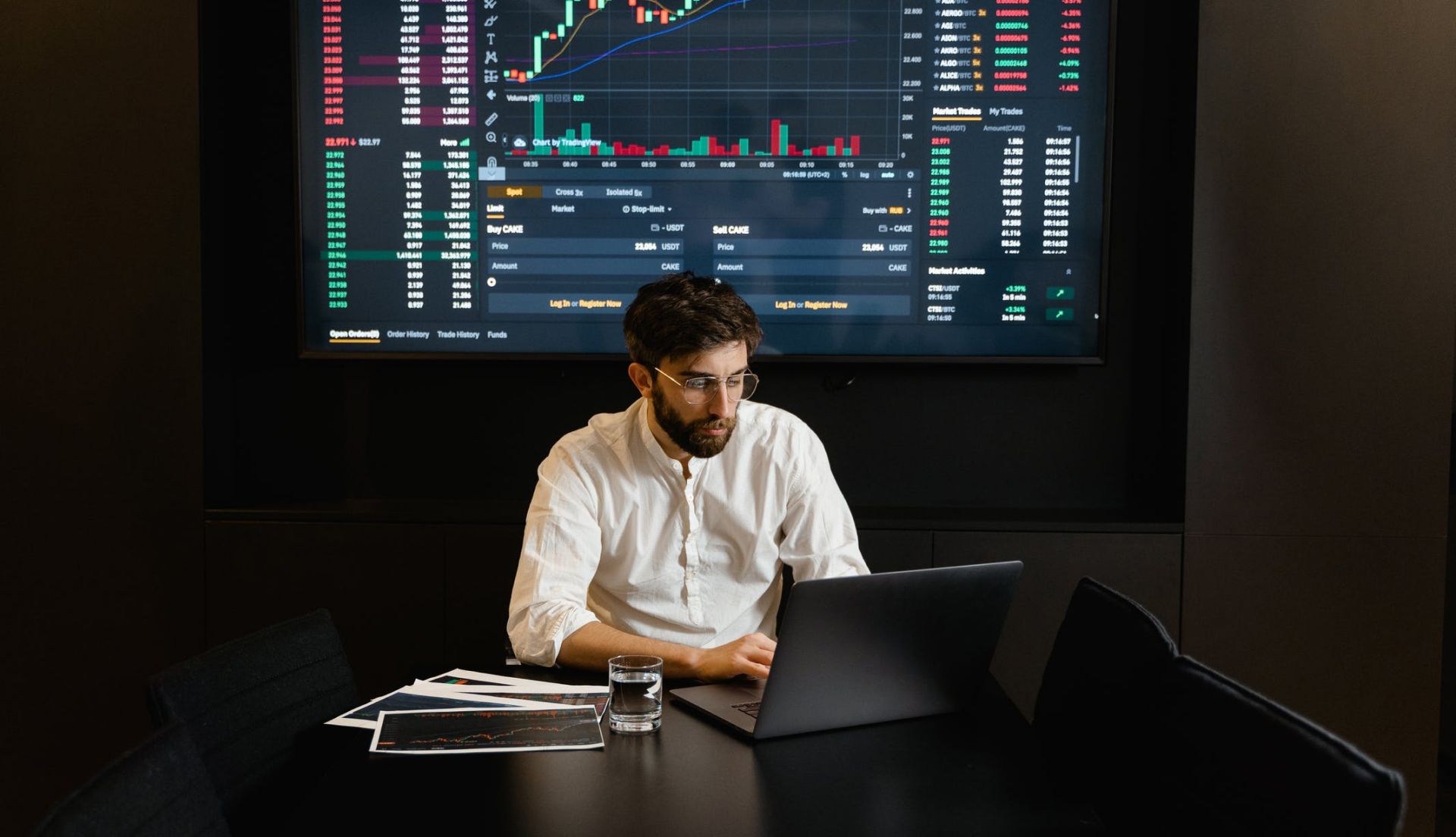 man working on laptop in front of financial data display